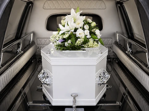 White casket with floral spray inside hearse