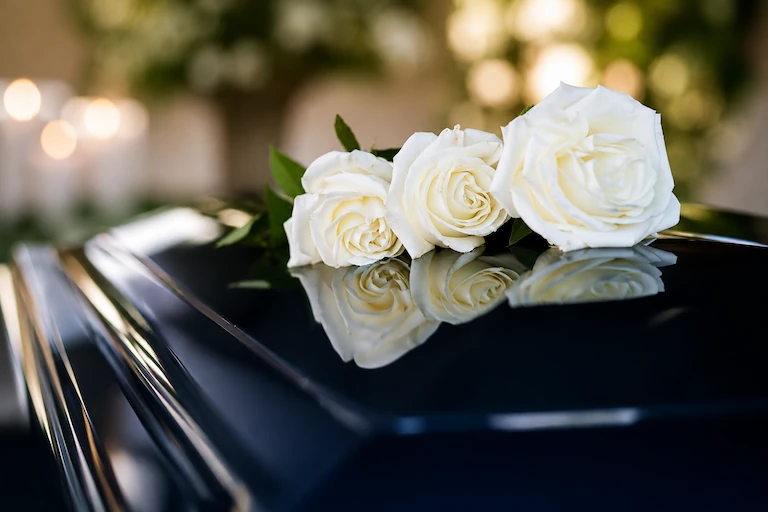 White roses resting on a dark casket